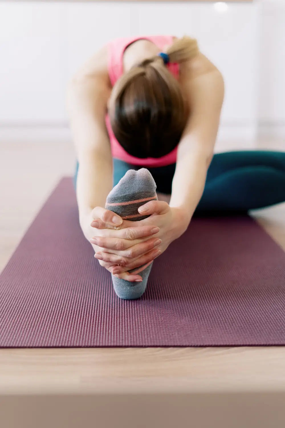 Person stretching on a yoga mat with a pink background