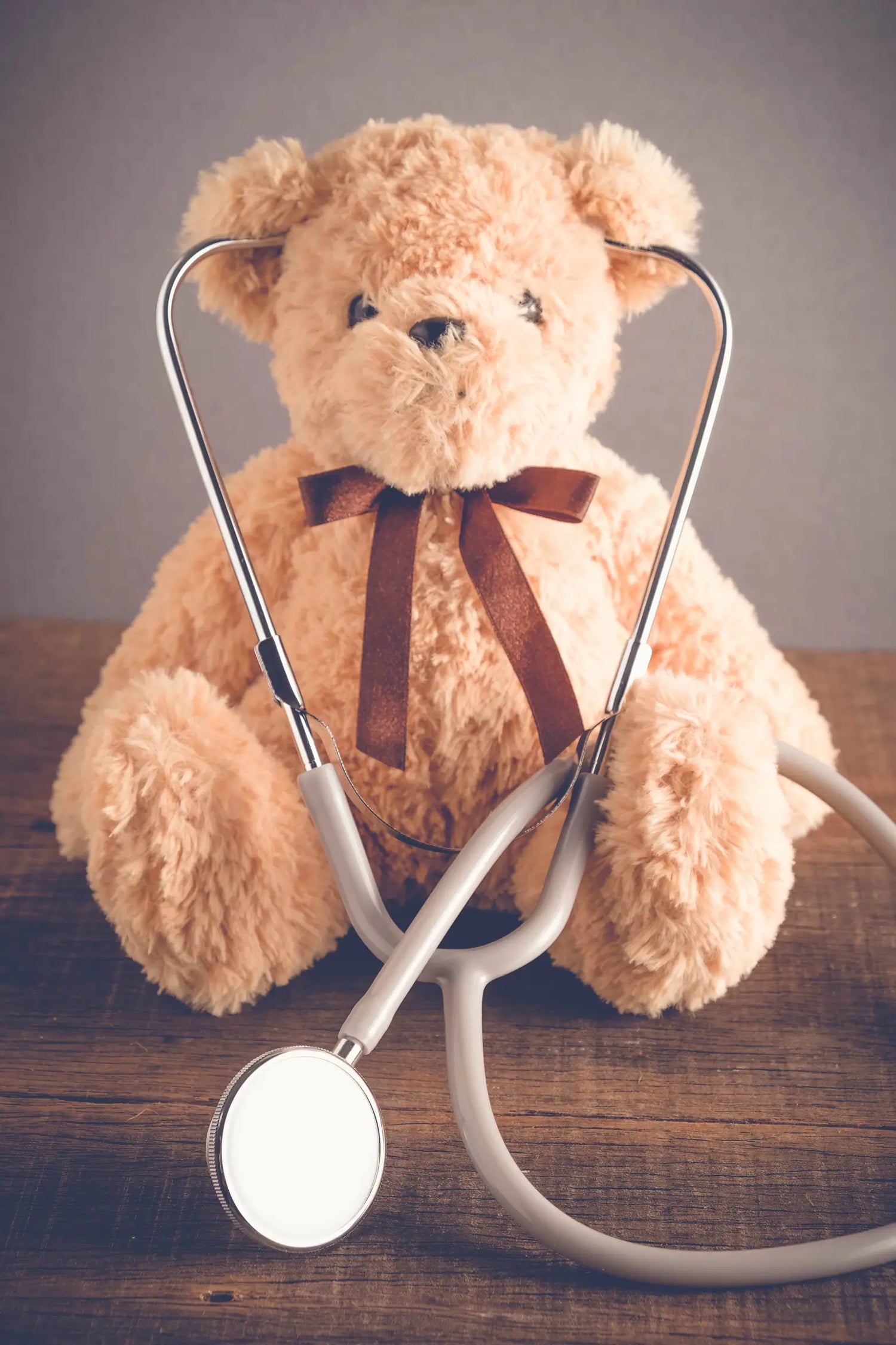Teddy bear with a stethoscope on a wooden surface