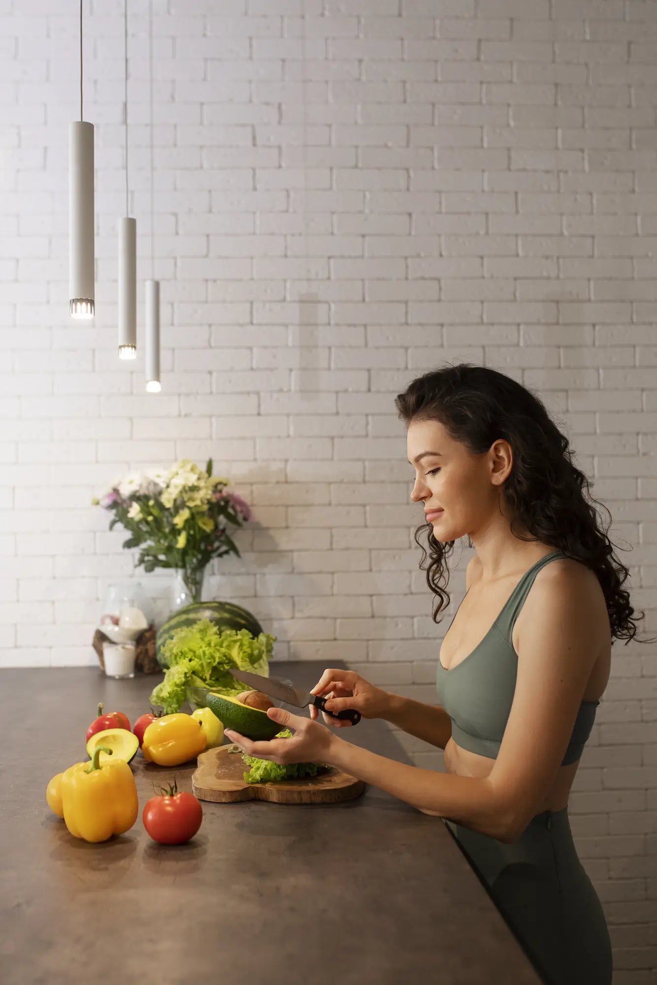 Woman preparing vegetables in a kitchen with a white tiled wall.